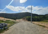 Rua pavimentada do loteamento com paisagem verde — Loteamento Bella Vista